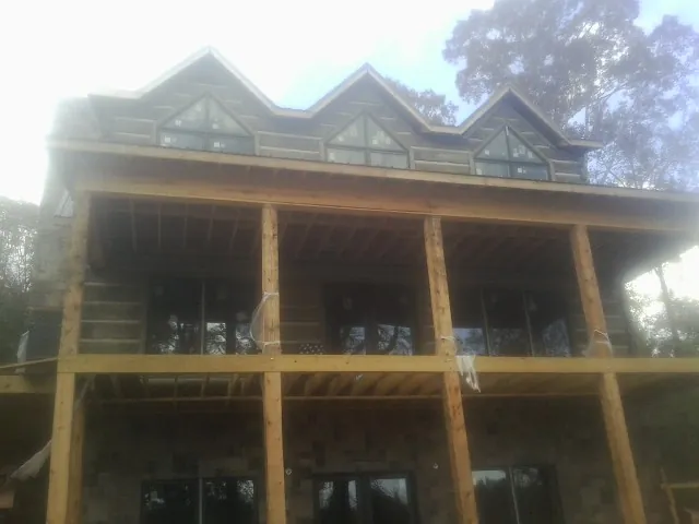 Dormers and porch framing on a large log home under construction — Roof Coating work by our crew in Hopewell