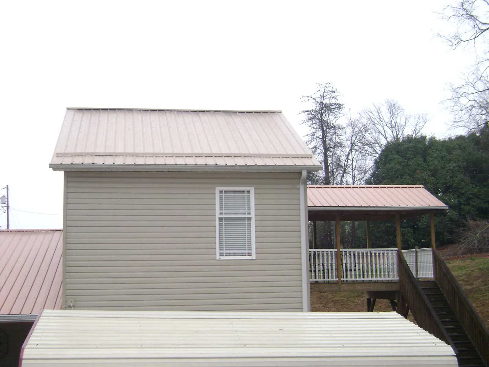 Tan metal roofs on a two story addition and attached porch, from a Roof Replacement job in Hopewell